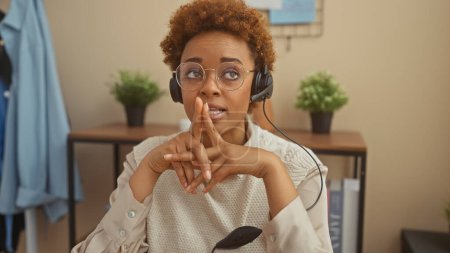 Téléchargez les photos : An african american woman working from home with headphones and a smartwatch in a cozy living room setting - en image libre de droit