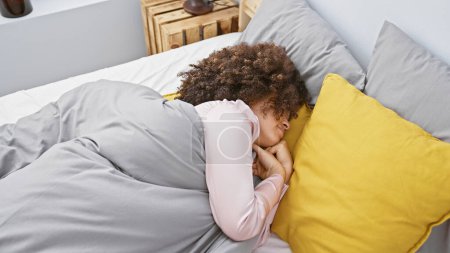 Young hispanic woman with curly hair sleeping in a cozy bedroom, embodying tranquility and comfort at home.