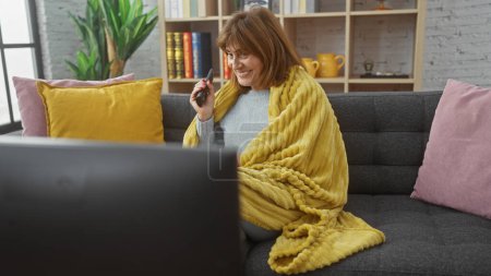 Frau mittleren Alters entspannt mit Fernbedienung auf Couch im gemütlichen Wohnzimmer