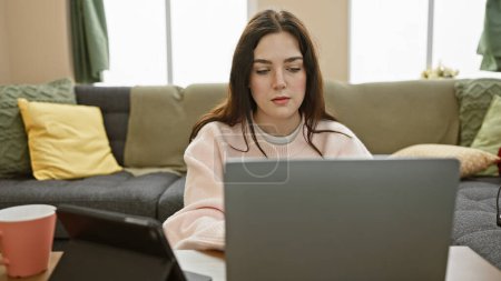 Focused young woman using laptop in a cozy living room interior