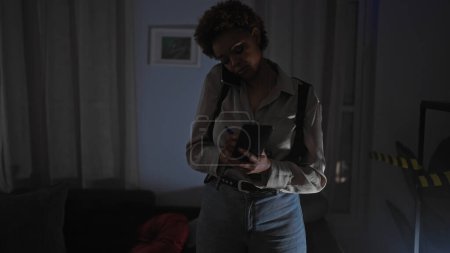 Afroamerikanerin macht sich während eines Telefonats in einem schwach beleuchteten Indoor-Tatort Notizen