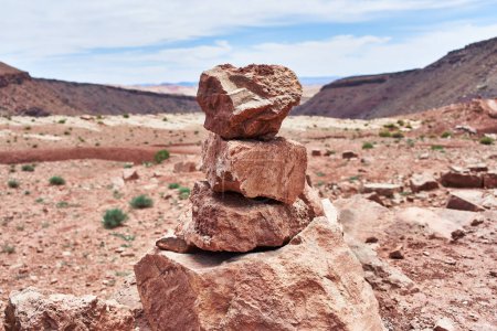 Piled stones balance in the serene, arid desert under a clear sky, evoking tranquility and natural beauty.