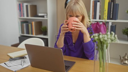 Photo for Blonde woman drinking coffee and using laptop in a cozy home interior, embodying a sense of casual elegance. - Royalty Free Image