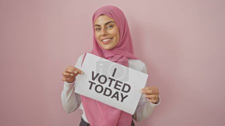 Una mujer alegre sosteniendo un cartel que dice 'he votado hoy' contra un fondo rosa encarna la participación democrática.