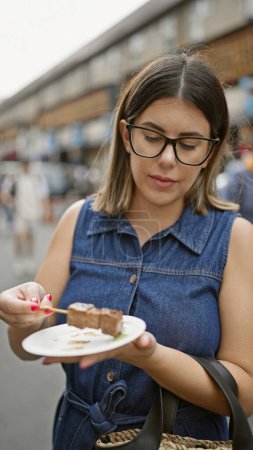 Téléchargez les photos : Superbe femme hispanique avec des verres saveurs fraîches wagyu boeuf bâton repas à la traditionnelle tsukiji marché extérieur street shop, tokyo - en image libre de droit