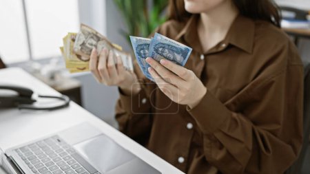 A young woman counts hungarian forints at her office desk, symbolizing financial transactions or budgeting.