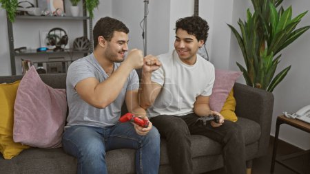 Two men fist-bumping while playing video games together in a cozy living room