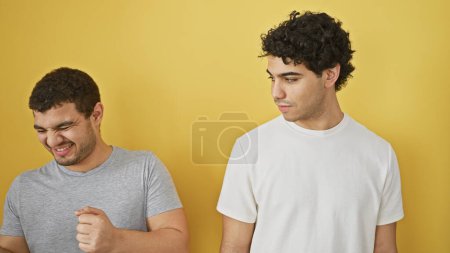 Two men expressing contrasting emotions over a yellow backdrop, epitomizing friendship or brotherhood in an isolated setting.