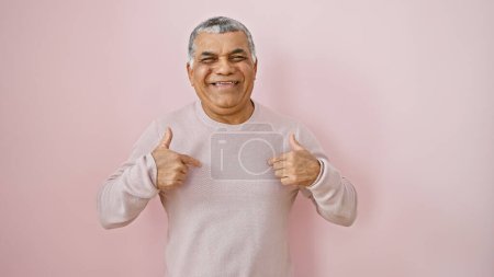 Smiling middle-aged man with grey hair giving thumbs up against a pink isolated background