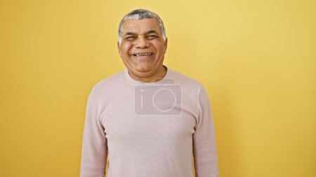 A smiling middle-aged man posing confidently against a vibrant yellow background, exuding charm and maturity.