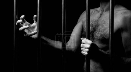 Foto de Hombre entre rejas de hierro con las manos mostrando ira, concepto de encarcelamiento - Imagen libre de derechos