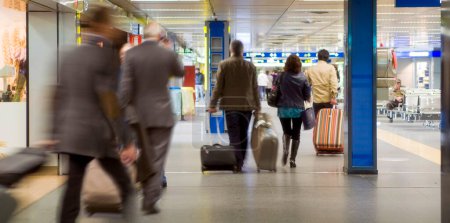 Foto de Interior del aeropuerto con los pasajeros arrastrando su equipaje e ir a la puerta - Imagen libre de derechos