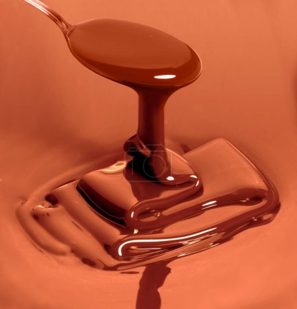 Photo for Melted dark chocolate as it is poured by a spoon to make a dessert - Royalty Free Image