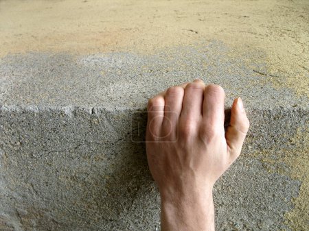 Foto de Hand clinging to a concrete block, concept of risk or strength - Imagen libre de derechos