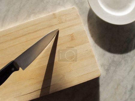 Foto de Cuchillo de cocina grande en una bandeja de madera sobre un escritorio de mármol - Imagen libre de derechos