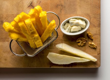 Foto de Tabla de cortar de madera con palos de polenta, pera, nueces y queso - Imagen libre de derechos