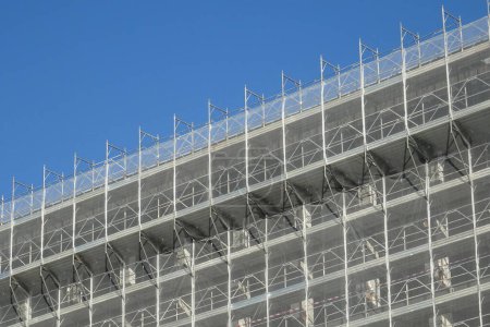 Foto de Renovación de la fachada exterior de un edificio, andamios metálicos con red de protección - Imagen libre de derechos