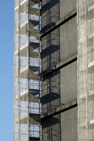 Foto de Renovación de la fachada exterior de un edificio, andamios metálicos con red protectora - vista de perspectiva - Imagen libre de derechos