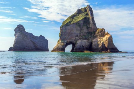 Photo for Beautiful rock formations reflect in the water at Wharariki Beach, New Zealand - Royalty Free Image