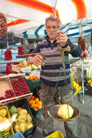 Photo for Naples, Italy, April 23, 2015: A street vendor weighs Local lemons, which are the pride of the region. in Vico Equense, Campania province, Naples region, Italy - Royalty Free Image