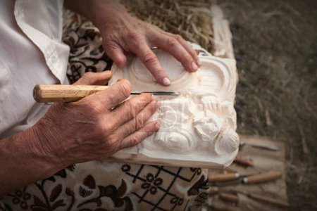Téléchargez les photos : Popular artisan carving in wood in his atelier. Moldavian  folk art. - en image libre de droit