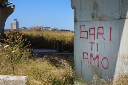 Foto de BARI, ITALIA - JULIO 2023: Italiano "Bari Ti Amo" - el texto "Bari I love you" rociado con pintura en un muelle de puente de hormigón. En el fondo la cervecería Peroni - Imagen libre de derechos