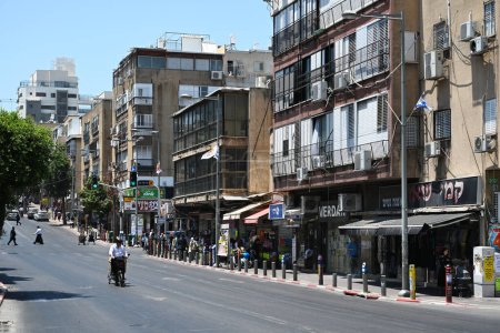 Foto de BNEI BRAK, ISRAEL - 23 DE MAYO DE 2023: El hombre en paseos en bicicleta a través del rabino Akiva St., una calle comercial principal en el centro de la ciudad de Bnei Brak. - Imagen libre de derechos