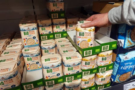 Photo for GERMANY - JANUARY 2024: Shopper buys Private label brand Bio organic Oat flakes in a Lidl supermarket - Royalty Free Image
