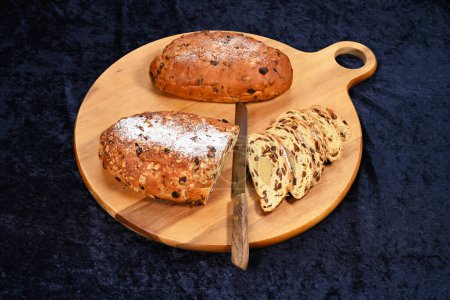 Christmas stollen served on a round wooden board. Kerststol is a traditional Dutch oval-shaped fruited Christmas bread is eaten during the holidays