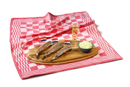 Arenque con banderas holandesas en plato con cebollas picadas y chupito de korenwijn, un manjar tradicional holandés