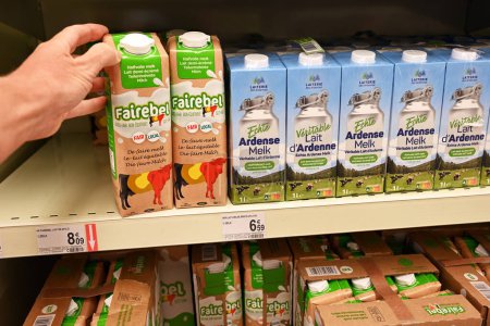 Foto de WALLONIA, BÉLGICA - 14 DE AGOSTO DE 2023: El comprador selecciona una caja de leche en fila de las marcas Fairebel y Laiterie des Ardennes Producto regional originario de las Ardenas belgas, en un supermercado - Imagen libre de derechos