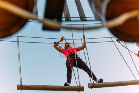 Junge Frau balanciert im Erlebnispark auf Holzplanke