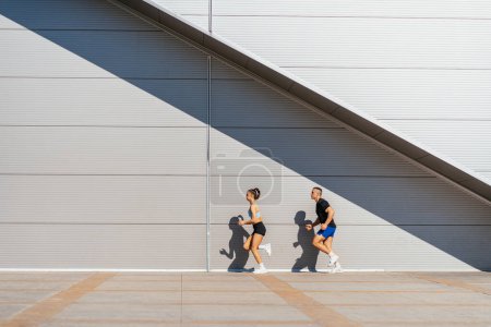Hacer ejercicio en un día soleado. Preciosa pareja corriendo en una fila
