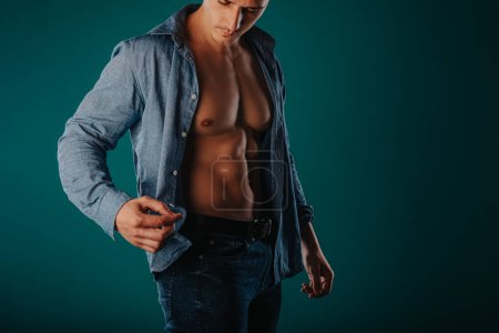Stunning and muscular man standing in a green room and posing