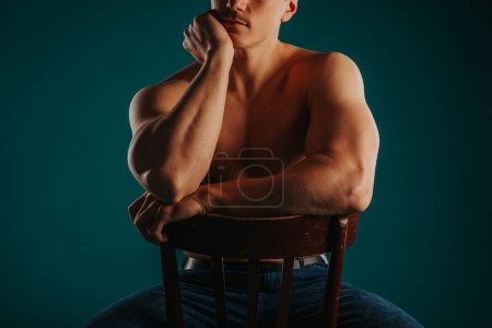 Teilaufnahme eines fitten Bodybuilders, der auf einem Stuhl sitzt und für die Kamera posiert