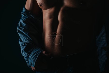 Silhouette photo of strong fit man showing his abs while holding a belt. Close up photo