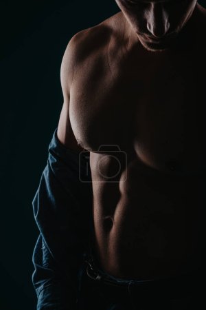 Der Mann zeigt seinen fitten Körper, konzentriert sich auf die Brust. Silhouettenfoto.