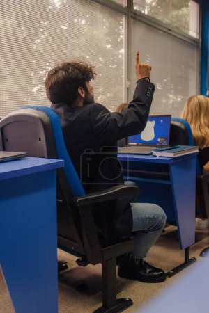 Estudiante universitario levantando la mano para hacer una pregunta.