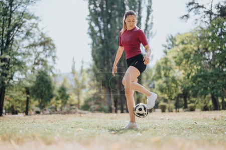 Attraktive Mädchen genießen Fußball-Freestyling im sonnigen Park