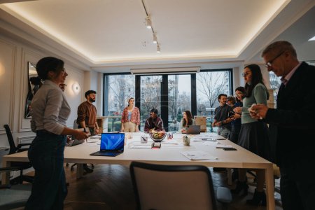 Une scène de bureau dynamique capturant un groupe diversifié de professionnels participant activement à une réunion d'équipe collaborative, la lumière naturelle remplissant l'espace de travail moderne.