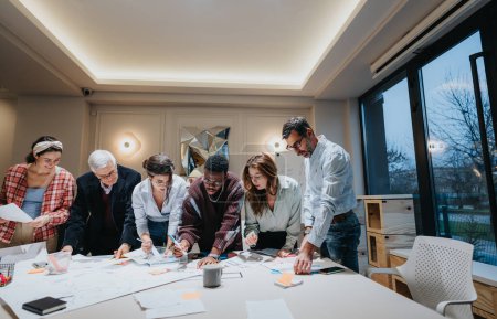 Ein mehrgenerationenübergreifendes Team von Mitarbeitern nimmt aktiv an einem kollaborativen Geschäftstreffen in einem gut beleuchteten, modernen Büroraum teil..