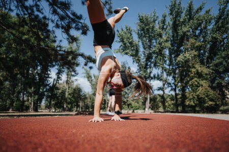 Active women training and enjoying a sunny day in the park, doing cartwheels and stretching. They embrace a healthy lifestyle and have fun exercising outdoors in a natural environment.