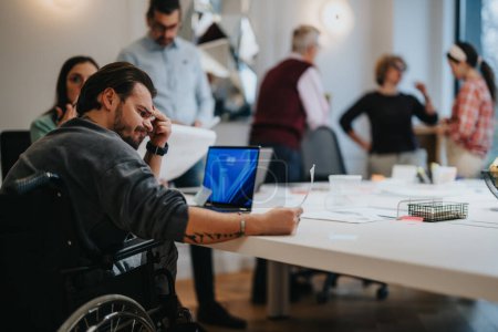 Konzentriertes Team aus verschiedenen Fachleuten, darunter ein Mann im Rollstuhl, das in einem modernen Büroumfeld zusammenarbeitet.