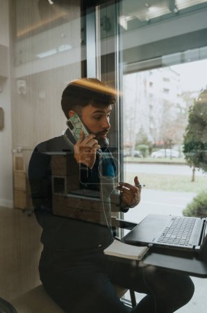 Enthusiastic entrepreneur discussing business strategies and profitability on a private phone call in an office phone booth.