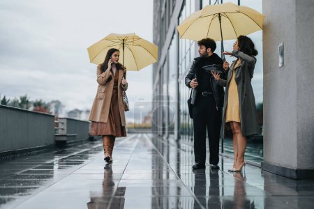 Two women and a man in business attire using yellow umbrellas on a wet city sidewalk, showcasing urban life during the rainy season.