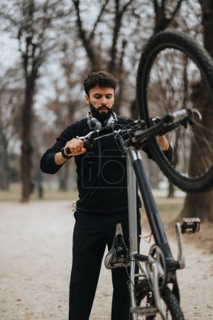 Ein engagierter Geschäftsmann in Freizeitkleidung stellt die Gangschaltung seines Fahrrads in einem Outdoor-Umfeld ein und präsentiert Multitasking und einen gesunden Lebensstil.