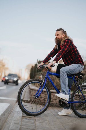 Empresario barbudo en bicicleta en un entorno urbano, mostrando una forma ecológica alternativa de trabajar y abrazando la movilidad moderna.