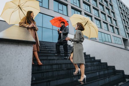 Drei Profis mit bunten Regenschirmen navigieren auf nassen Stufen durch die Stadt und zeigen eine Szene des städtischen Alltags und des Pendelns bei schlechtem Wetter.