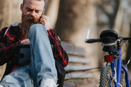 Konzentrierter Geschäftsmann in Freizeitkleidung, der im urbanen Stadtgebiet neben seinem Fahrrad an einem Tablet arbeitet.