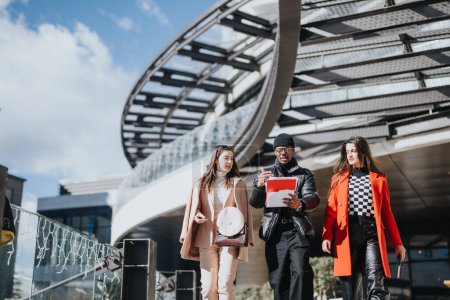 Three young people walk together in an urban setting, engaged in a lively conversation with a tablet in hand, conveying collaboration and diversity.